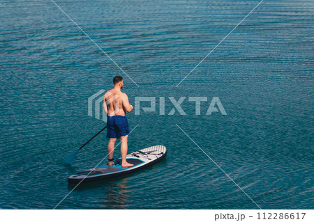 man balancing on supboard paddling 112286617