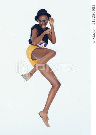 Funny, portrait and black woman with fashion, jumping and confident girl on white studio background. African person, hipster and model with glasses or pose with happiness, excited and casual outfit Funny, portrait and black woman with fashion, jumping and confident girl on white studio background. African person, hipster and model with glasses or pose with happiness, excited and casual outfit 112286983
