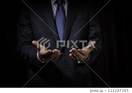 黒背景に手を差し出すジェスチャーのビジネスマン 112287165