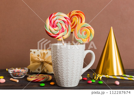 Colorful candies in cup on table on light background background. Large swirled lollipops. Creative concept of a jar full of delicious sweets from the candy store 112287674