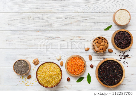 Various superfoods in smal bowl on colored background. Superfood as rice, chia, quinoa, lentils, nuts, sesame seeds, almonds. top view copy space Various superfoods in smal bowl on colored background. Superfood as rice, chia, quinoa, lentils, nuts, sesame seeds, almonds. top view copy space 112287700