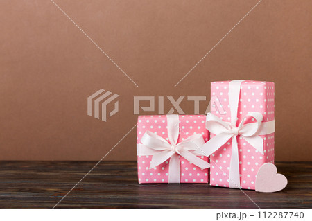 gift box with red bow and red heart on colored background. Perspective view. Flat lay 112287740