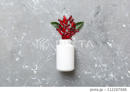 different drugs and health supplement pills poured from a medicine bottle health care and medical top view on colored background 112287886