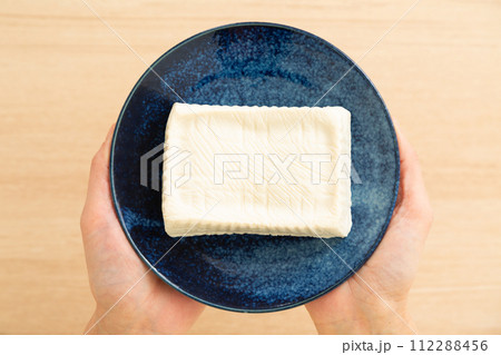 手作りの木綿豆腐のお皿を持つ女性の手元 手作りの木綿豆腐のお皿を持つ女性の手元 112288456