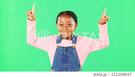 Children, pointing and a black girl on a green screen background in studio for marketing a product. Kids, portrait and advertising with a cute little female child showing space on chromakey mockup 112289037