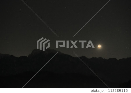 宵闇の星が瞬く中、地球照の月齢2.2三日月が南アルプス甲斐駒ケ岳の山並みに沈む 112289116