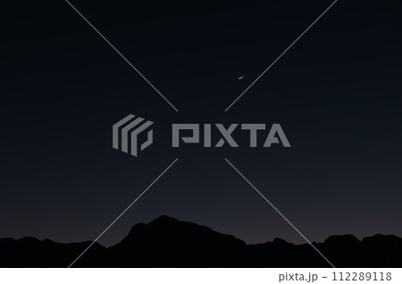 ブルーアワーの南アルプス甲斐駒ケ岳の上に月齢2.2の三日月 112289118