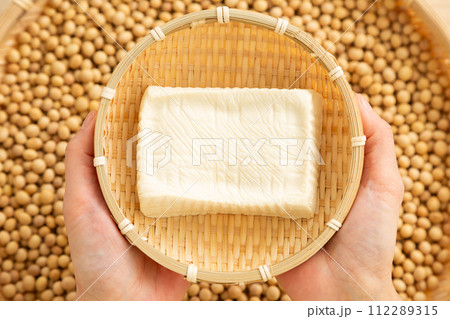 ざるに入った手作りの木綿豆腐を持つ女性の手元 112289315