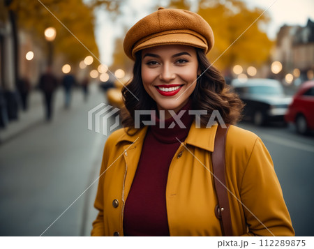 A woman in a yellow coat and red sweater is smiling and posing for a picture 112289875