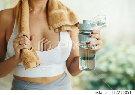 Cropped image of fit woman holding towel and bottle of fresh water 112290051