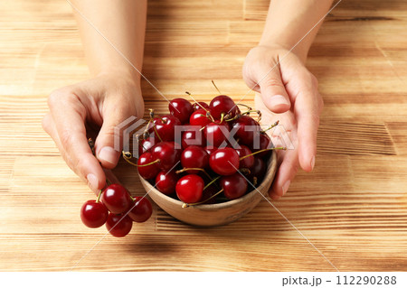 Ripe cherry fruits in a bowl on a wooden background Ripe cherry fruits in a bowl on a wooden background 112290288