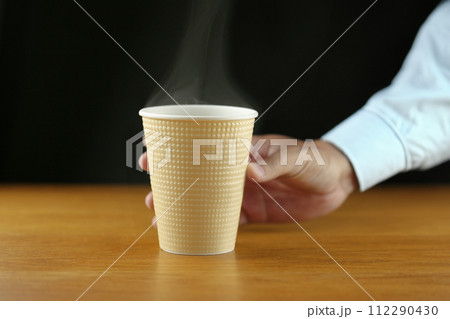 ホットコーヒーが入った紙コップとそれを持つ男性の手　AI生成画像 112290430