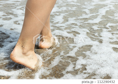 A man walks barefoot on the sand on the beach. 112290432