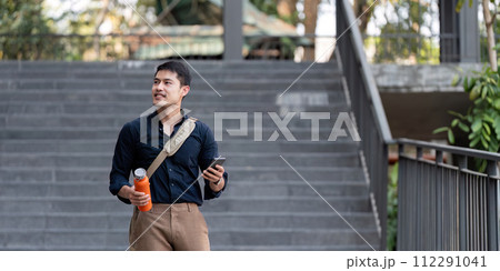 Smiling asian businessman walking to work while to hold reusable eco friendly ecological cup in the city 112291041