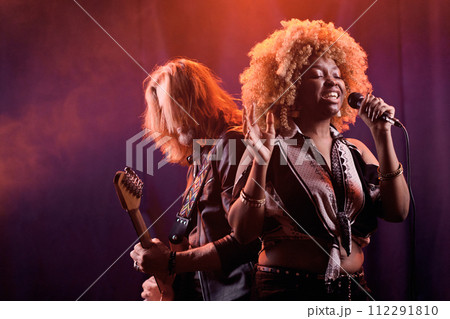 Waist up portrait of music band performing on stage in smoky nightclub with real African American woman singing to microphone copy space Waist up portrait of music band performing on stage in smoky nightclub with real African American woman singing to microphone copy space 112291810