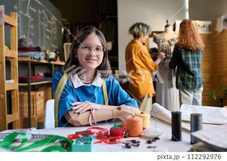 Portrait of teen young girl with arm prosthetic smiling at camera in atelier workshop copy space 112292976