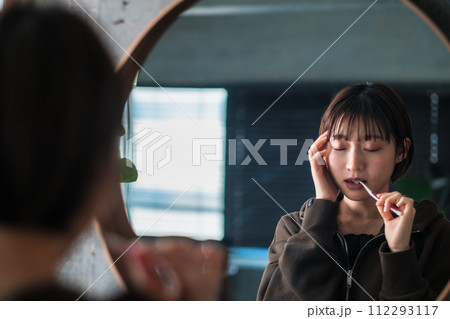 朝洗面台の鏡の前で歯を磨く女性 朝洗面台の鏡の前で歯を磨く女性 112293117