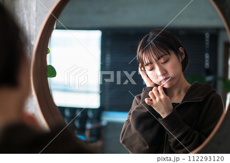 朝洗面台の鏡の前で歯を磨く女性 112293120