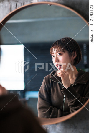 朝洗面台の鏡の前で歯を磨く女性 112293123