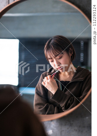 朝洗面台の鏡の前で歯を磨く女性 112293124