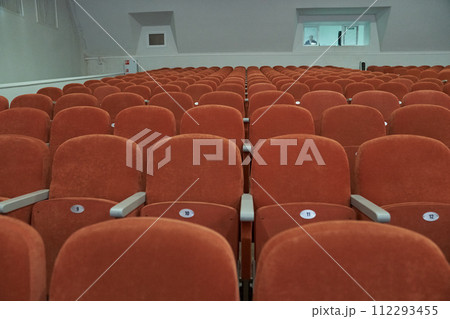 Empty cinema hall with orange seats with copy space. Seats with numbers in theatre. 112293455