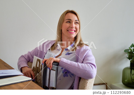 A beautiful model with a smile on her face and a magazine in her hands 112293680