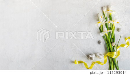Bouquet of white Iris flowers, yellow ribbon, quail eggs, small ceramic bunnies on white Copy space Bouquet of white Iris flowers, yellow ribbon, quail eggs, small ceramic bunnies on white Copy space 112293914