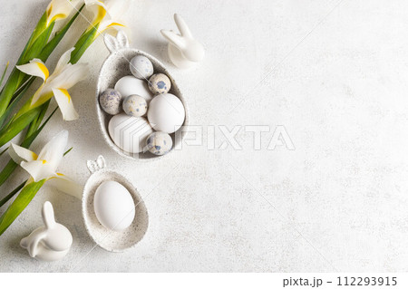 Trendy monochrome white Easter card with eggs in marble bowls with bunny ears, bunnies, Iris flowers 112293915
