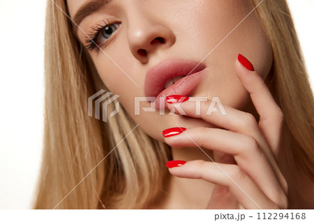 Cropped close-up image of tender young girl with smooth, spotless skin, nude makeup and red nails isolated against white studio background 112294168
