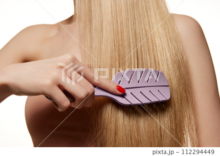 Cropped image of female straight blonde hair. Woman brushing hair, taking care isolated against white studio background 112294449