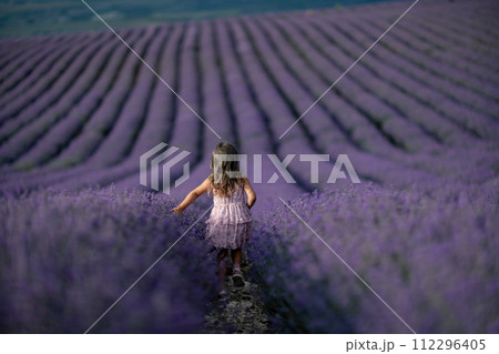 Lavender field girl. Back view happy girl in pink dress with flowing hair runs through a lilac field of lavender. Aromatherapy travel Lavender field girl. Back view happy girl in pink dress with flowing hair runs through a lilac field of lavender. Aromatherapy travel 112296405