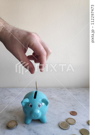 Feeding the piggy bank with euro coins 112297473