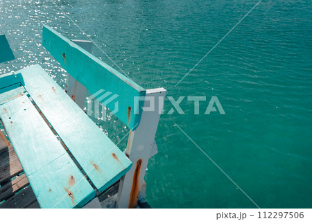A wooden rowboat gently glides on the calm blue water of a ocean A wooden rowboat gently glides on the calm blue water of a ocean 112297506