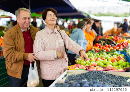 Elderly man and a woman buy berries at an open air market 112297626