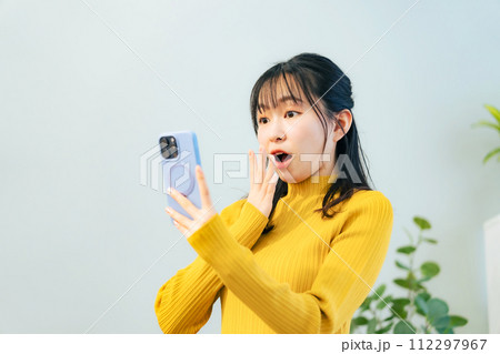 スマホを見て驚く女性 112297967