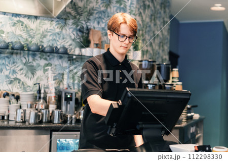 Young waiter serving customer at cash point in cafe. Man working with POS terminal. Student working part-time. Problems of unemployment and Job opportunities for youth. Small business vacancies. Young waiter serving customer at cash point in cafe. Man working with POS terminal. Student working part-time. Problems of unemployment and Job opportunities for youth. Small business vacancies. 112298330