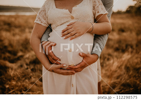 hands of future mother and father clasped pregnant big tummy. 112298575