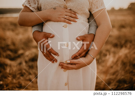 hands of future mother and father clasped pregnant big tummy. 112298576