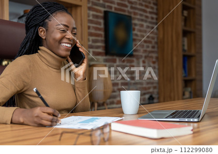 Smiling woman with dreadlocks working with laptop and smartphone is freelance entrepreneur 112299080