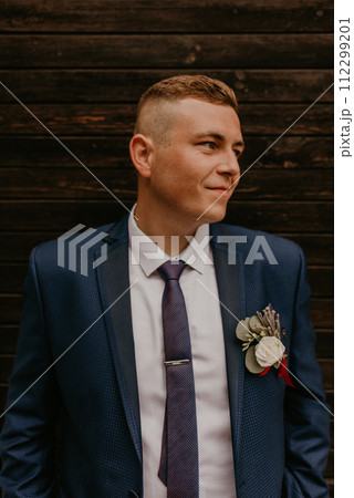 Caucasian young man groom in navy blue suit white shirt and tie looking to the side. Caucasian young man groom in navy blue suit white shirt and tie looking to the side. 112299201