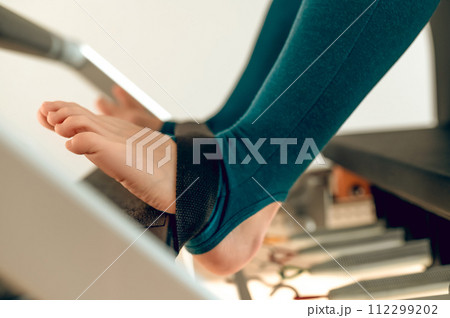 Woman legs on reformer machine for full-body Pilates workout Woman legs on reformer machine for full-body Pilates workout 112299202