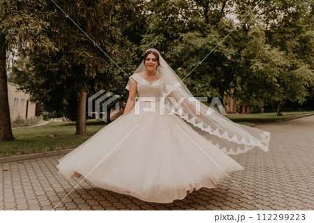 Caucasian young woman bride spinning whirls dancing posing moving at nature 112299223