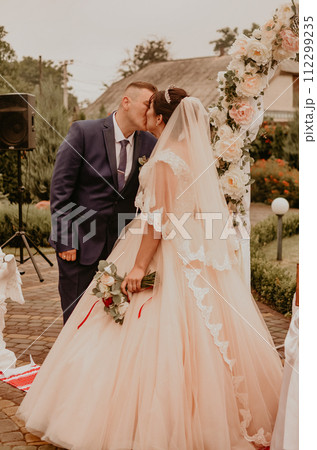 wedding ceremony on the background of a flower arch laughing kissing 112299235