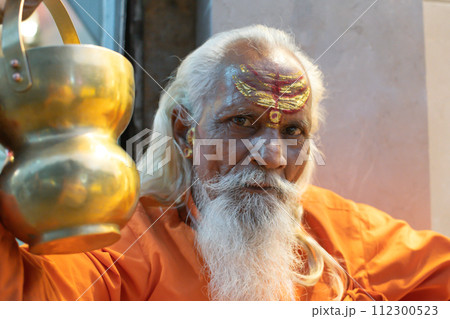Ascetic monk Sadhu in India with beard, white hair and painted face preaching 112300523
