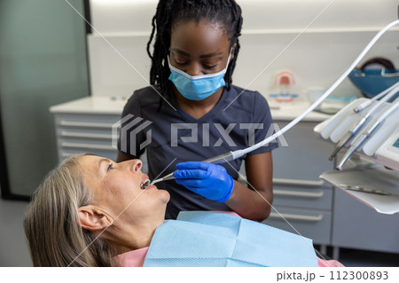 Woman patient sitting in dental chair at medical center while professional doctor fixing her teeth 112300893