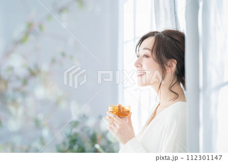 窓辺でお茶を飲む女性 112301147
