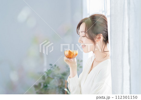 窓辺でお茶を飲む女性 112301150