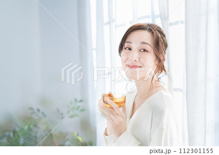 窓辺でお茶を飲む女性 112301155