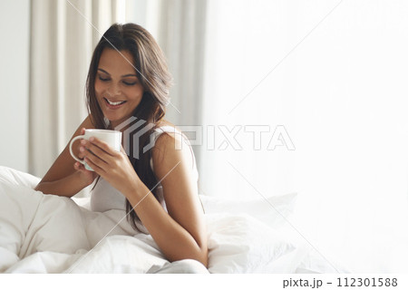 Happy, calm and woman with coffee in bedroom with caffeine to wake up in morning at home. Smile, relax and comfy young female person drinking mug of cappuccino, espresso or latte in apartment. Happy, calm and woman with coffee in bedroom with caffeine to wake up in morning at home. Smile, relax and comfy young female person drinking mug of cappuccino, espresso or latte in apartment. 112301588