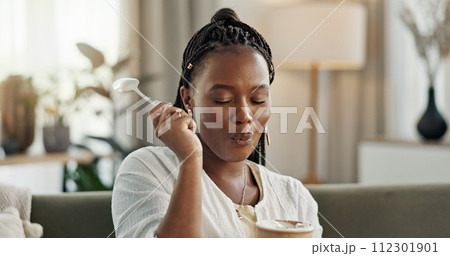 Black woman on sofa, eating ice cream and relax in living room with smile, summer pleasure and enjoy. Happiness, fun or thinking, girl on couch with taste of frozen chocolate getalo dessert in home. Black woman on sofa, eating ice cream and relax in living room with smile, summer pleasure and enjoy. Happiness, fun or thinking, girl on couch with taste of frozen chocolate getalo dessert in home. 112301901